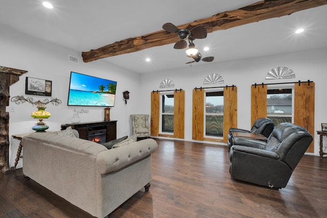 living room with beam ceiling, dark hardwood / wood-style flooring, a barn door, and ceiling fan