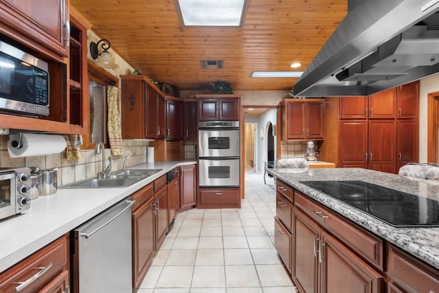 kitchen featuring island exhaust hood, tasteful backsplash, appliances with stainless steel finishes, and sink