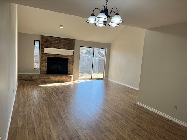 unfurnished living room with a fireplace, lofted ceiling, dark wood-type flooring, and a chandelier