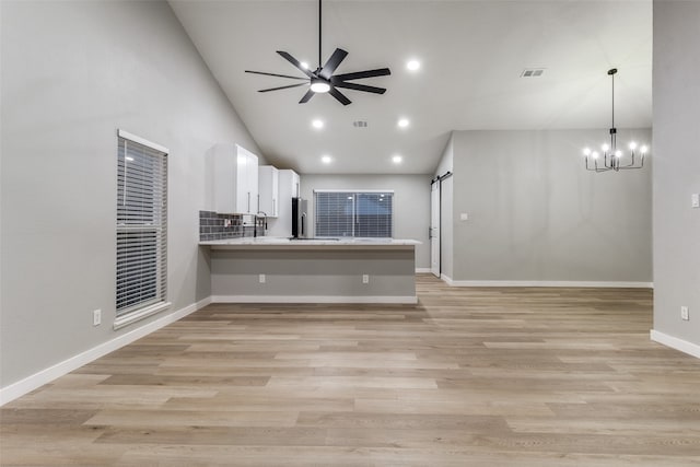 kitchen with kitchen peninsula, decorative light fixtures, light hardwood / wood-style flooring, white cabinetry, and a barn door