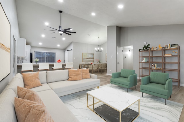 living room featuring ceiling fan with notable chandelier, light wood-type flooring, a barn door, and high vaulted ceiling