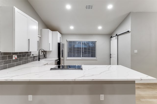 kitchen featuring white cabinetry, kitchen peninsula, a barn door, and sink