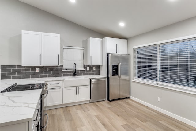 kitchen featuring appliances with stainless steel finishes, decorative backsplash, white cabinets, light stone countertops, and sink