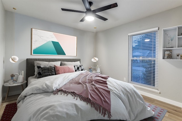 bedroom featuring multiple windows, wood-type flooring, and ceiling fan