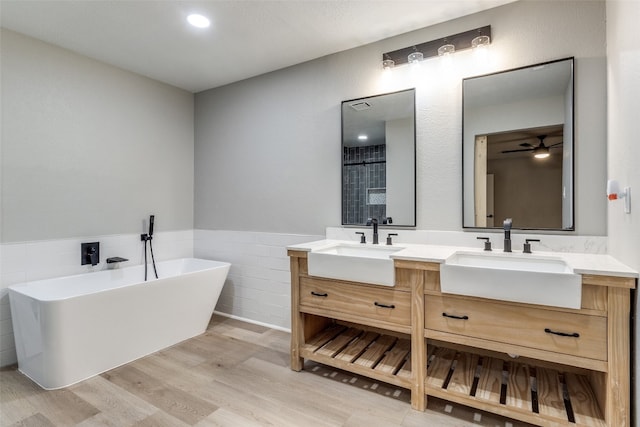 bathroom featuring tile walls, a bathing tub, vanity, and hardwood / wood-style floors