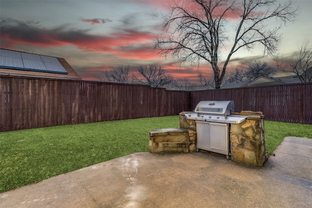 patio terrace at dusk featuring a lawn and area for grilling