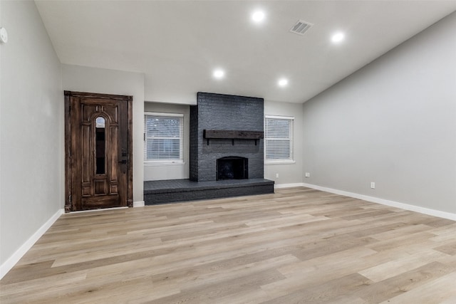 unfurnished living room with a brick fireplace and light wood-type flooring