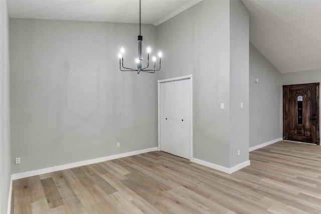 unfurnished dining area with an inviting chandelier, light hardwood / wood-style flooring, and lofted ceiling