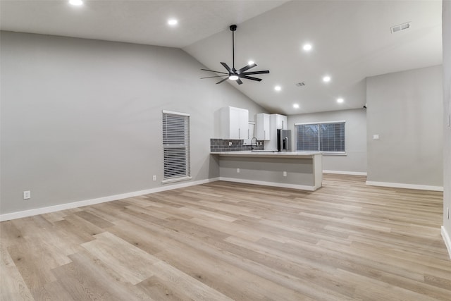 unfurnished living room with ceiling fan, sink, light hardwood / wood-style floors, and high vaulted ceiling