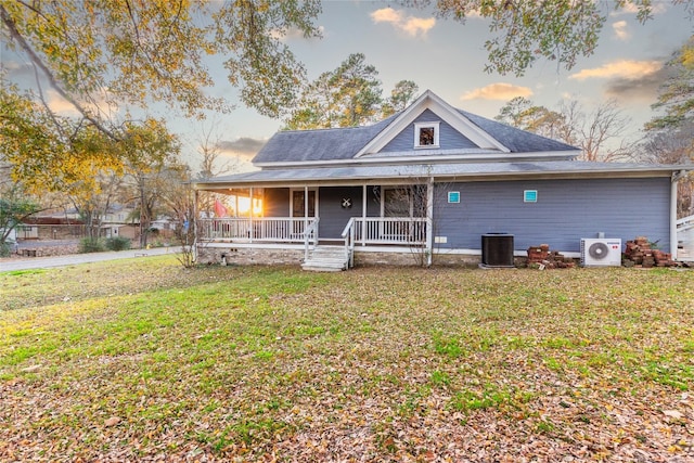 view of front of property featuring central air condition unit, covered porch, and a yard