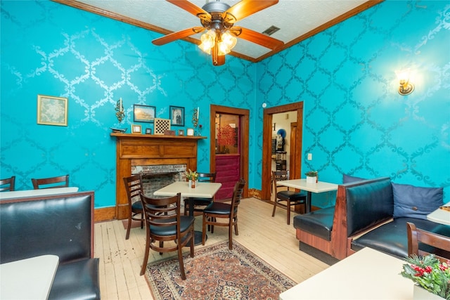 interior space with ornamental molding, a textured ceiling, ceiling fan, and light wood-type flooring