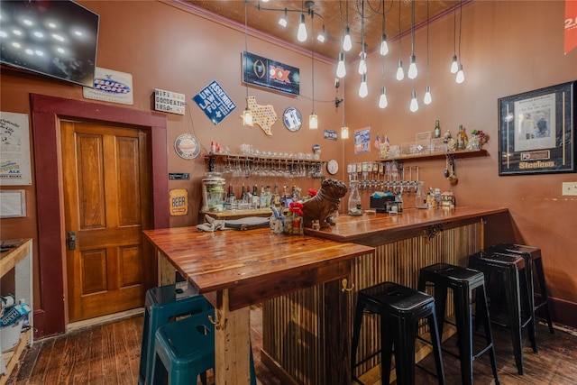 bar featuring dark hardwood / wood-style floors, ornamental molding, wooden counters, and hanging light fixtures