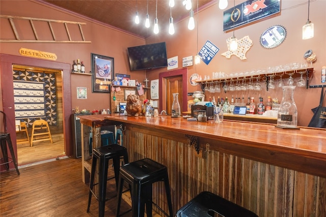 bar with dark hardwood / wood-style flooring, ornamental molding, butcher block countertops, and vaulted ceiling