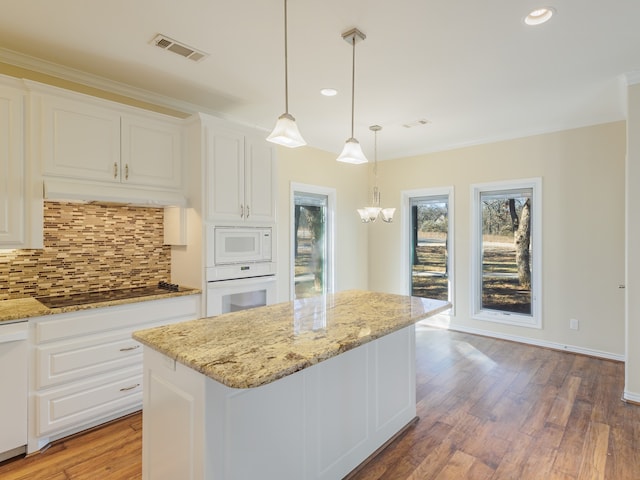 kitchen featuring pendant lighting, a center island, white appliances, and white cabinetry