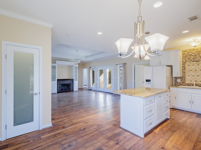 kitchen featuring white cabinets, pendant lighting, a kitchen island, white refrigerator with ice dispenser, and dark hardwood / wood-style flooring