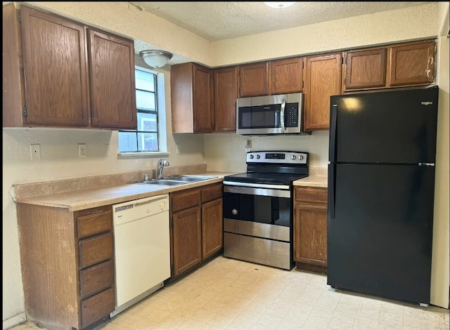 kitchen featuring appliances with stainless steel finishes, sink, and light tile flooring