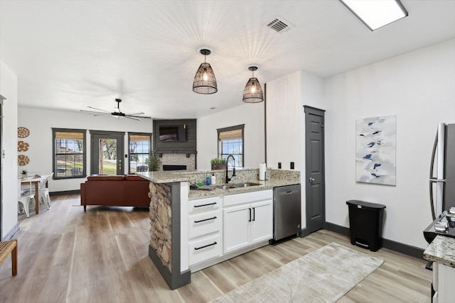 kitchen with ceiling fan, a large fireplace, light hardwood / wood-style flooring, white cabinets, and a wealth of natural light