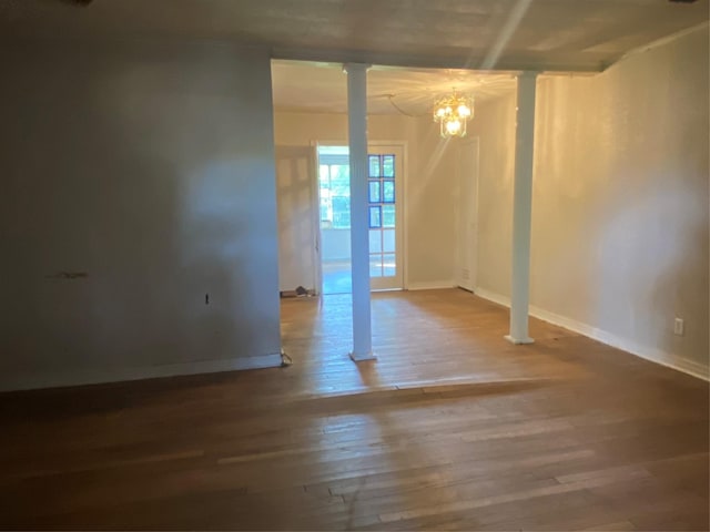 empty room with hardwood / wood-style flooring and an inviting chandelier