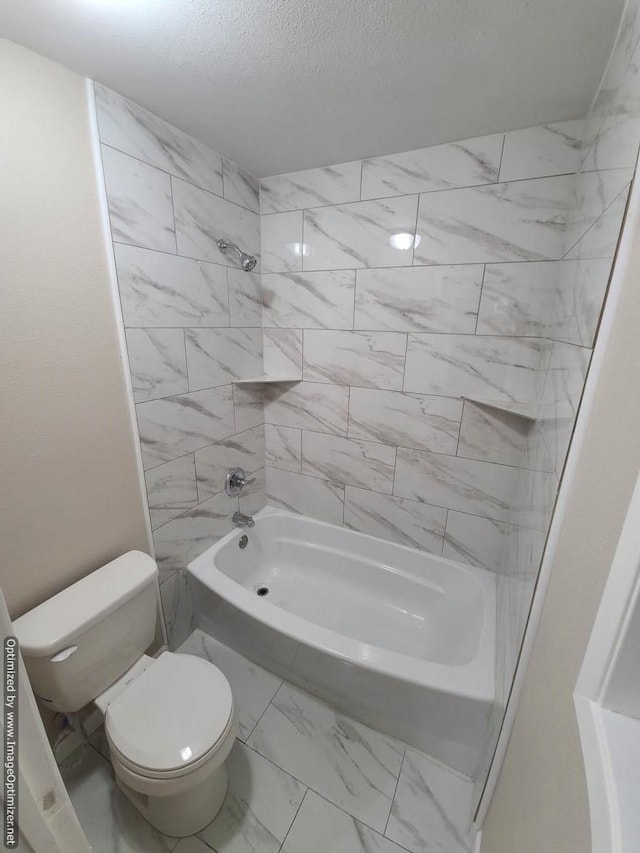 bathroom with toilet, shower / bathing tub combination, and a textured ceiling