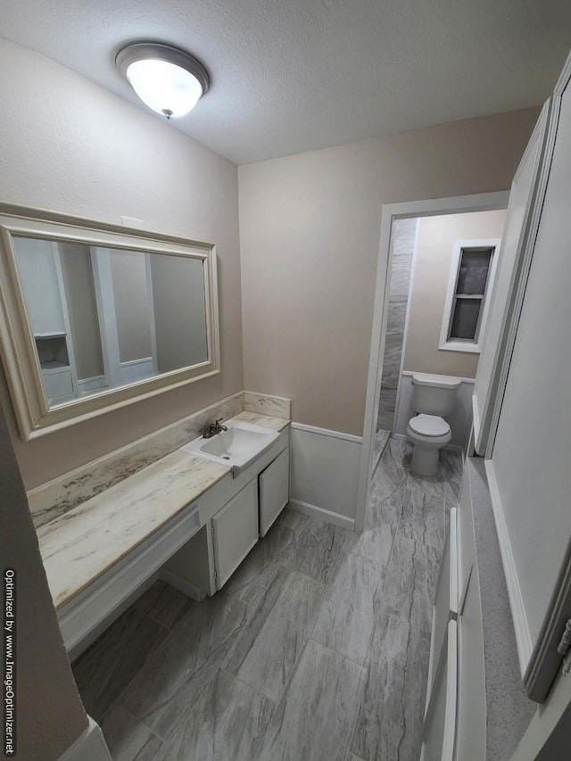 bathroom with vanity, toilet, and a textured ceiling