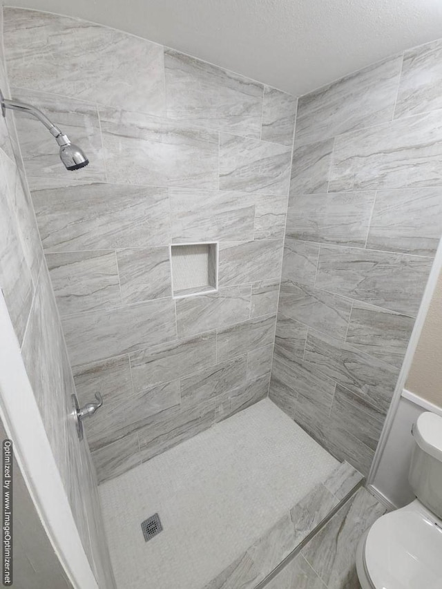 bathroom featuring toilet and a tile shower