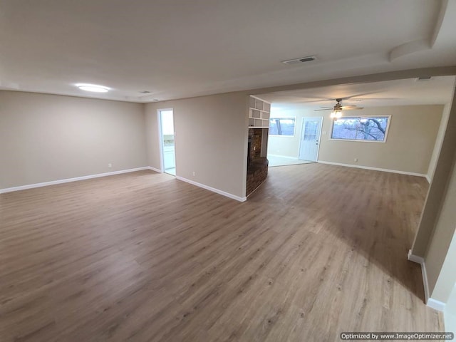 spare room featuring a fireplace, light hardwood / wood-style floors, and ceiling fan