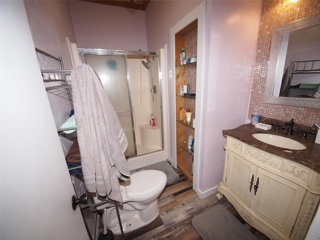 bathroom featuring backsplash, wood-type flooring, an enclosed shower, toilet, and vanity