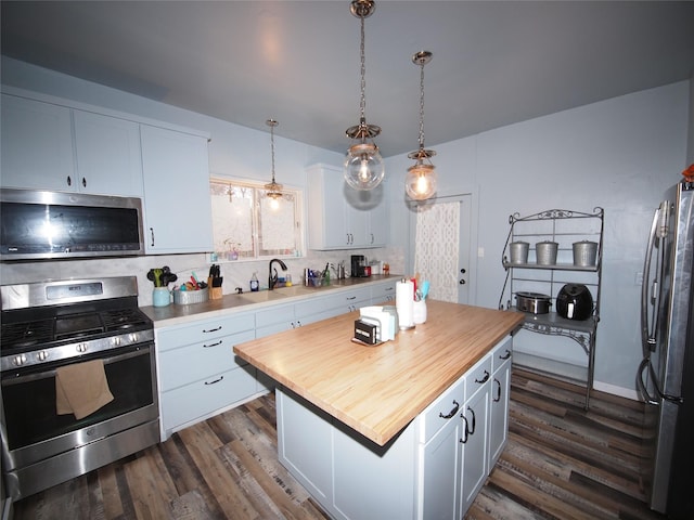 kitchen featuring stainless steel appliances, a center island, dark hardwood / wood-style floors, white cabinetry, and hanging light fixtures