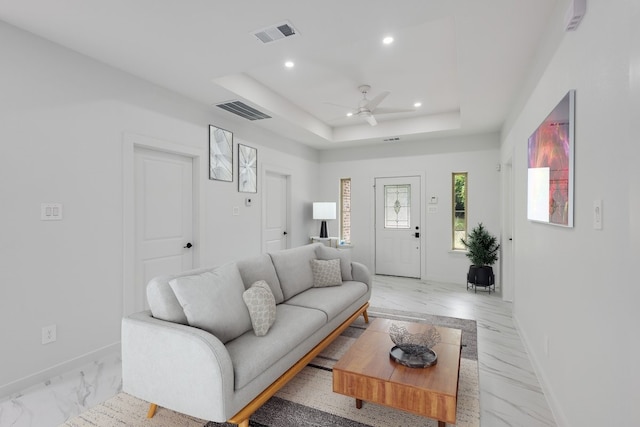 living room featuring ceiling fan and a raised ceiling