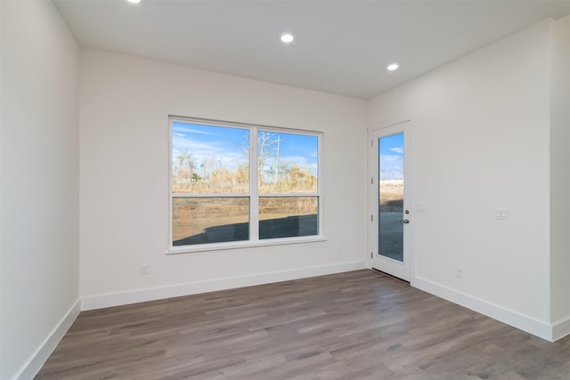 unfurnished room featuring recessed lighting, wood finished floors, and baseboards