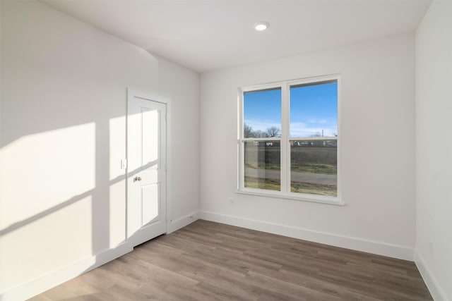 unfurnished room featuring recessed lighting, wood finished floors, and baseboards