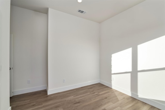 unfurnished room featuring baseboards, visible vents, and light wood-style floors