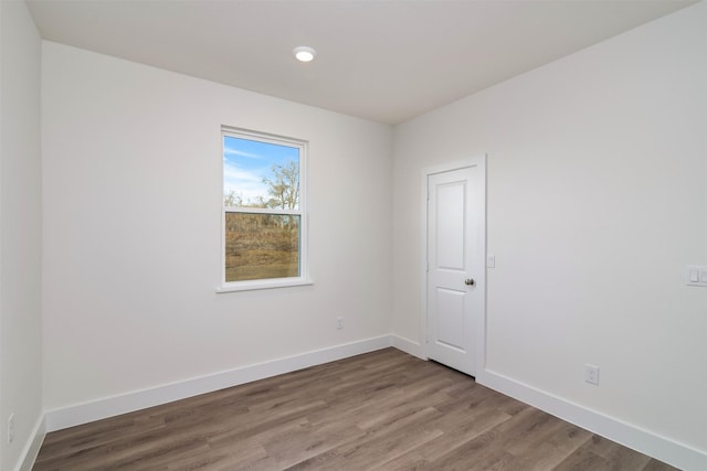 spare room featuring baseboards and wood finished floors