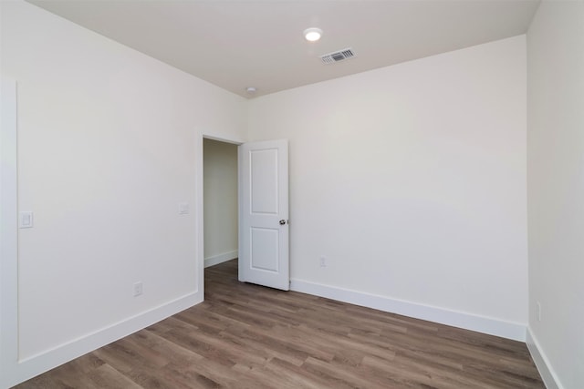 spare room featuring baseboards, visible vents, and wood finished floors