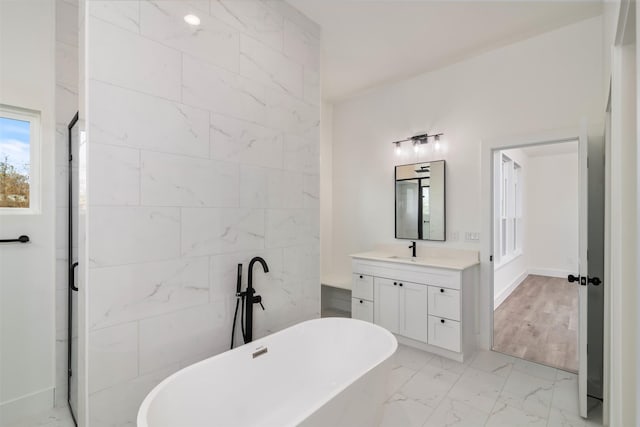 bathroom with marble finish floor, a shower stall, a soaking tub, and vanity