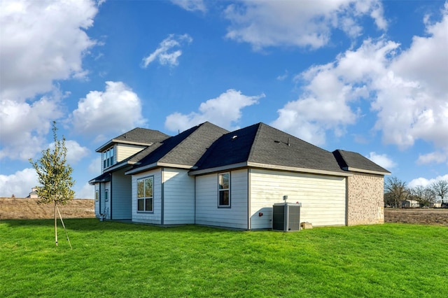 rear view of property featuring central air condition unit and a yard