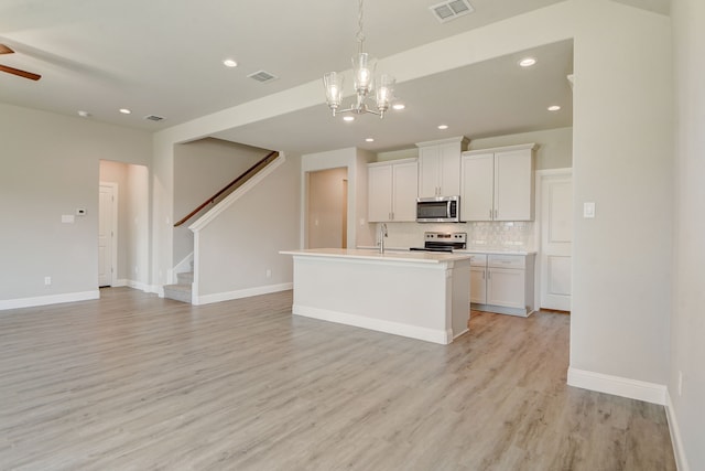 kitchen featuring sink, a center island with sink, white cabinetry, appliances with stainless steel finishes, and light wood-type flooring