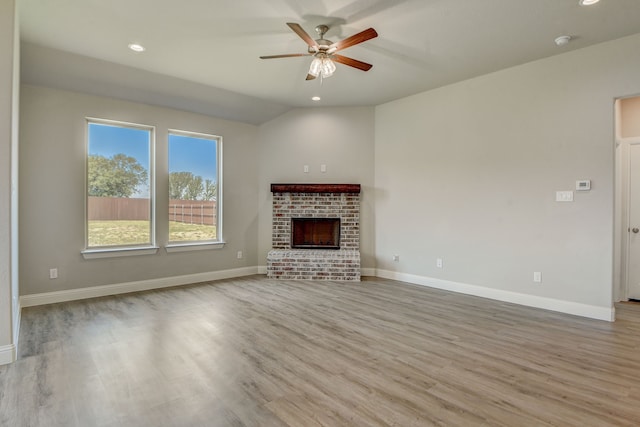 unfurnished living room featuring a fireplace, ceiling fan, vaulted ceiling, and light hardwood / wood-style floors