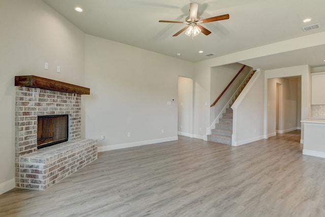 unfurnished living room with a brick fireplace, ceiling fan, and light hardwood / wood-style floors