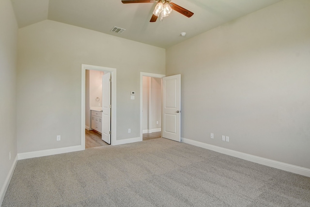 unfurnished bedroom featuring lofted ceiling, ceiling fan, light colored carpet, and ensuite bath