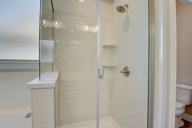 bathroom featuring toilet and a shower with shower door