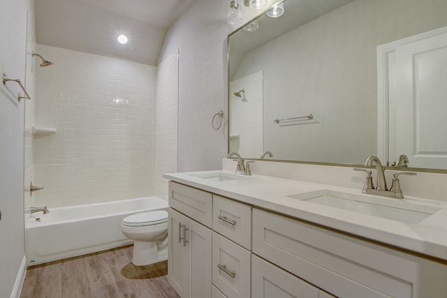 full bathroom with tiled shower / bath, hardwood / wood-style floors, vanity, and toilet