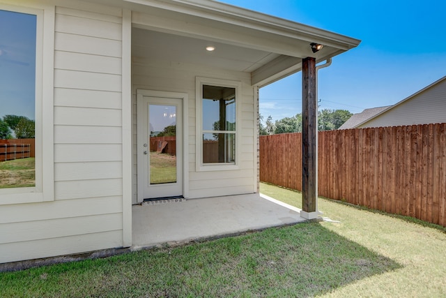 property entrance featuring a lawn and a patio area