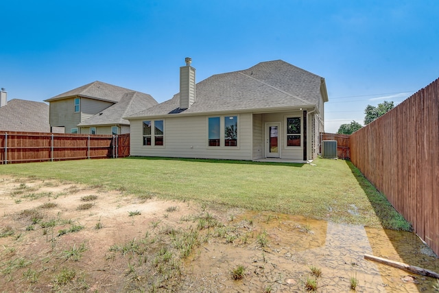 rear view of house with a yard and central AC