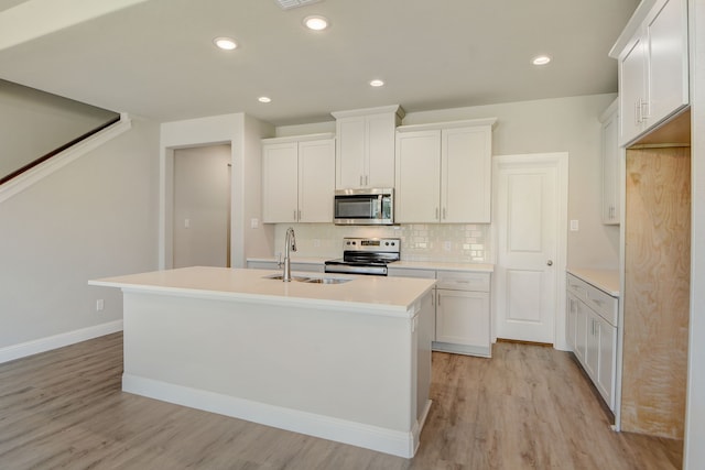 kitchen featuring a kitchen island with sink, light wood-type flooring, sink, stainless steel appliances, and white cabinetry