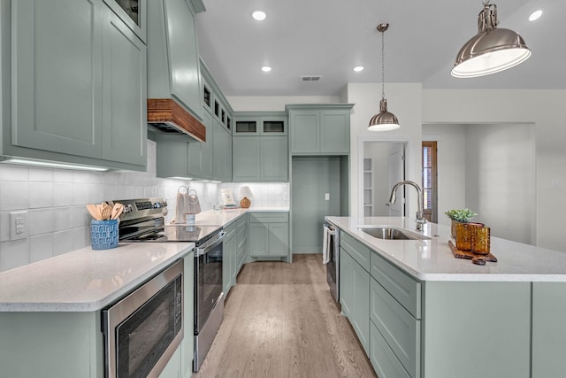 227 Rio Grande, Abilene, TX 79606 - kitchen featuring appliances with stainless steel finishes, light wood finished floors, an island with sink, tasteful backsplash, and decorative light fixtures