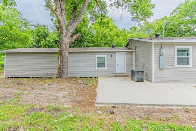 back of property with central AC unit and a patio