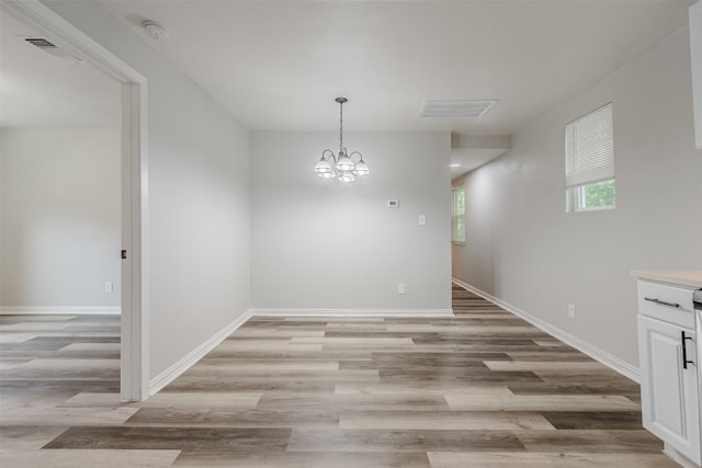 empty room featuring an inviting chandelier and light wood-type flooring