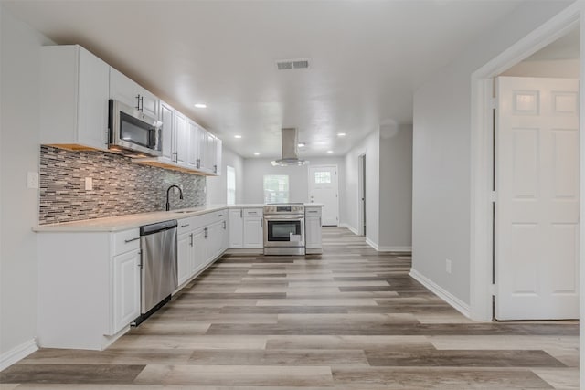 kitchen featuring appliances with stainless steel finishes, backsplash, light hardwood / wood-style flooring, and white cabinets