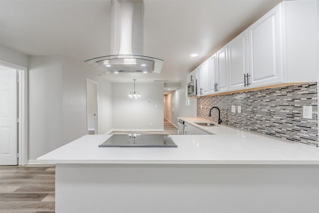 kitchen featuring pendant lighting, sink, light hardwood / wood-style floors, island range hood, and white cabinetry